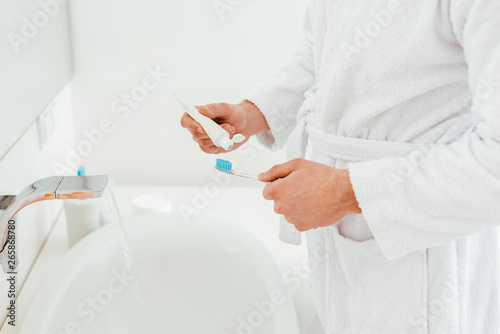 cropped view of man holding toothbrush and toothpaste near sink in bathroom © LIGHTFIELD STUDIOS