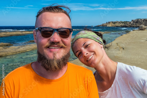 Self portrait of smiling couple tourists on vacations looking streight into camera with blue Mediterranean sea on background © Margarita