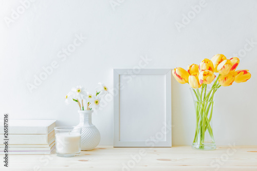 Home interior with decor elements. White frame, yellow tulips in a vase, interior decoration