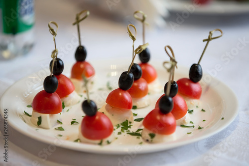 Buffet dishes.Slices of cheese with cherry tomatoes and olives