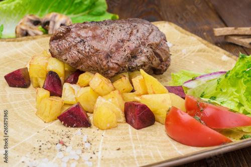 Steak with fried potatoes and fresh salad on a plate.