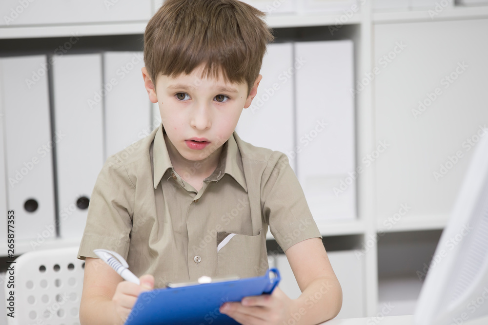 Junior school student does his homework. A boy with a pen in his hands writes something. A child solves a problem Junior school student does his homework. A boy with a pen in his hands writes something. A child solves a problem