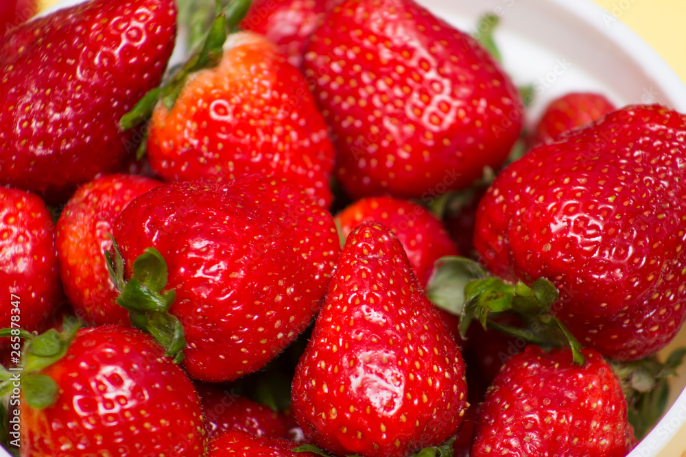 Fresh strawberries in bowl close up on yellow background Fresh strawberries in bowl close up on yellow background