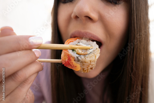 Sushi and mouth girl closeup. The girl eats sushi and rolls with chopsticks