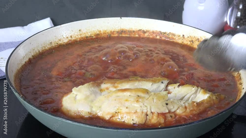 Returning chicken to a pan of simmering tomato sauce Returning chicken to a pan of simmering tomato sauce