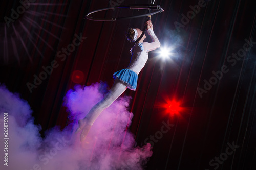 Performs a circus girl actress. Circus aerial gymnast on the hoop. Acrobatics. Teenager performs an acrobatic trick in the air
