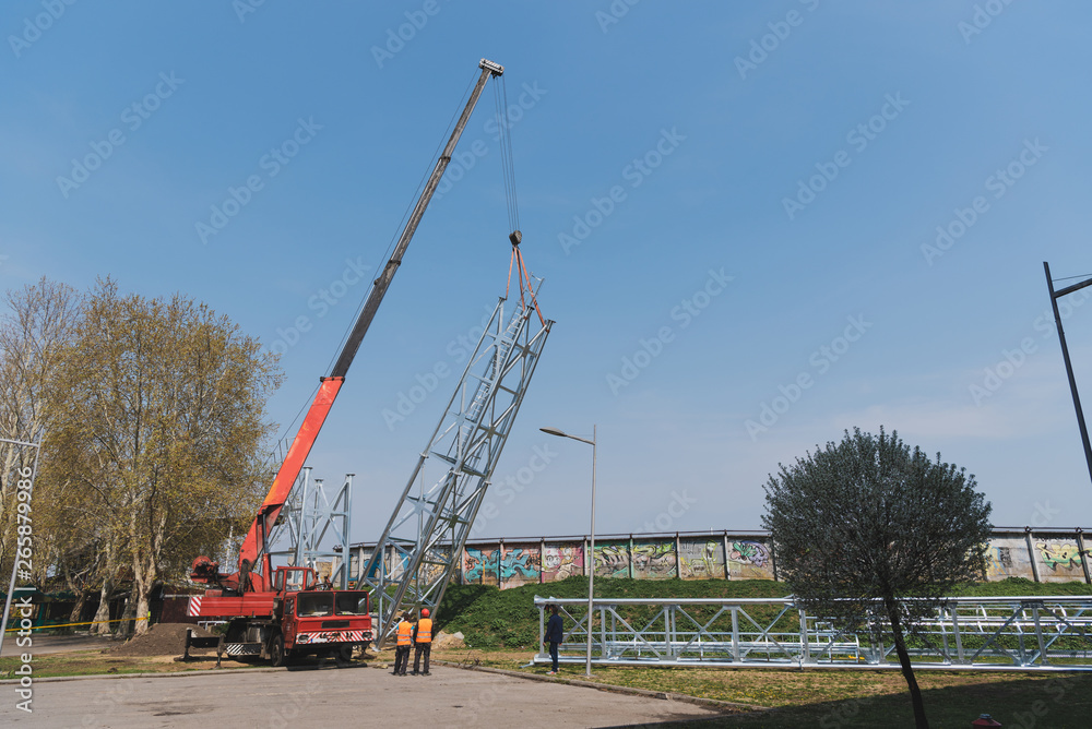 a large crane raises up the reflector structure