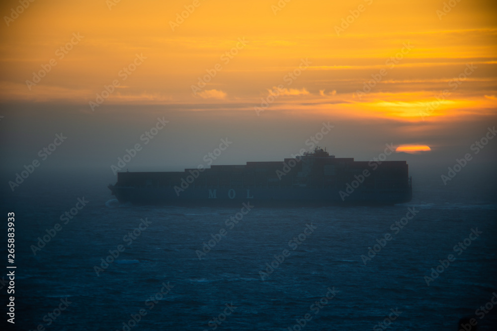 Misty tanker boat in fog against a colorful sunset