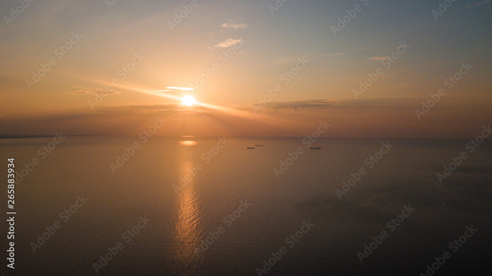 Dawn on the sea. The warm sun rises above the water. Photographed from the drone. Aerial photo shooting