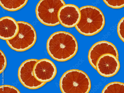 Creative pattern made of red oranges. top view of colorful fruit pattern of fresh red orange slices on blue colorful background. 