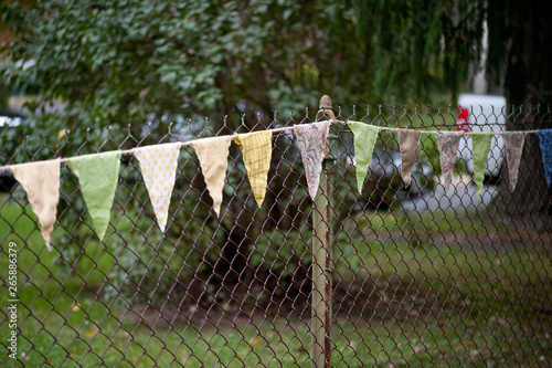 DIY fabric bunting hanging on fence at backyard wedding