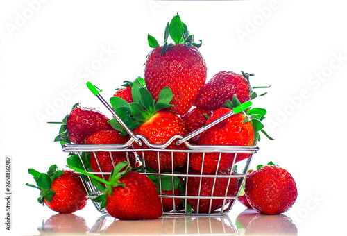 Self-service supermarket shopping basket with fresh strawberries, grocery products on a light background.