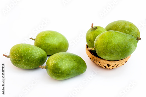 Raw organic kesar mangoes isolated on white in a basket along with some on surface. photo