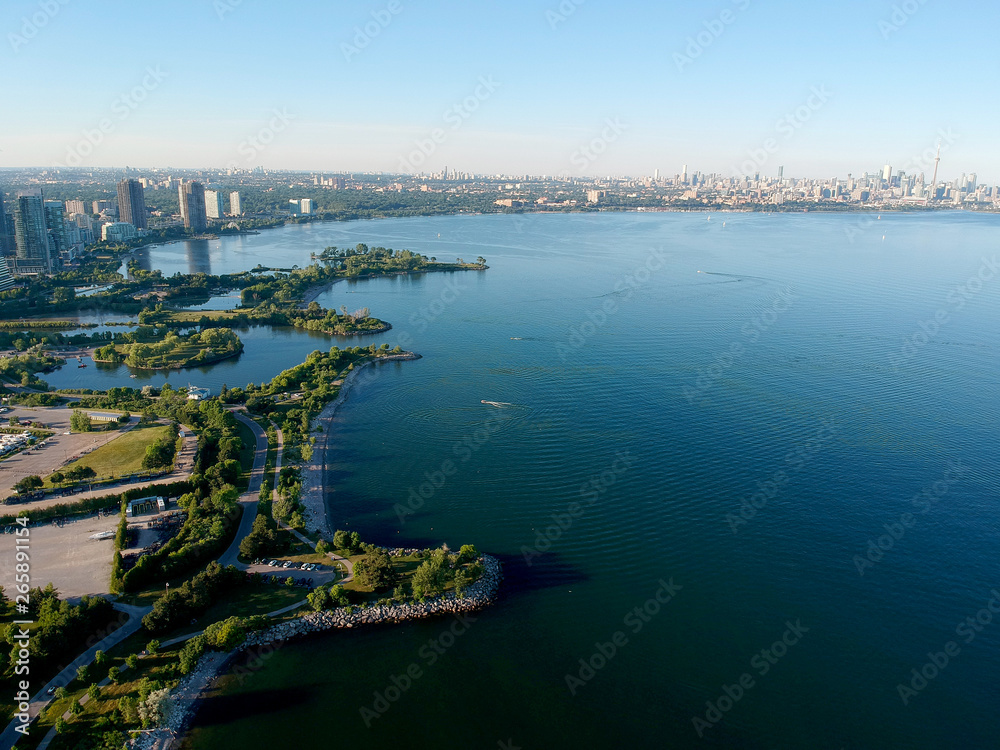 Aerial bird eye shot over Humber Bay Shores Park, Toronto, Canada with coastal condo homes, blue skies, beaches and harbour entrance in view with glass condominiums. Perfect summer day sunset.