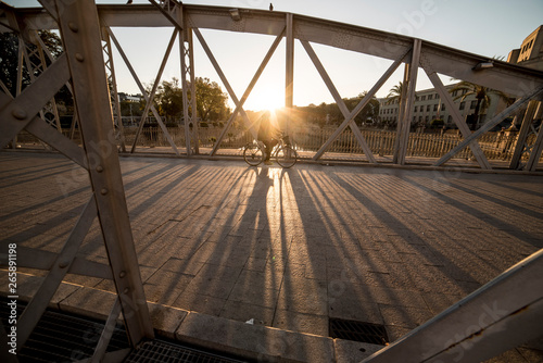  bicycle crossing iron bridge at sunrise