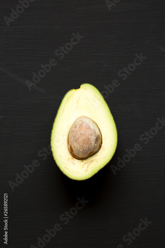 Halved avocado on a black background, top view. From above, overhead.