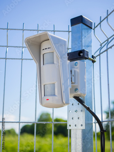 Motion sensor on open protected area. Installed on the fence and connected to the security system with wires. Multifunctional microwave detector. Outdoor guard. Concept of personal or object security. photo