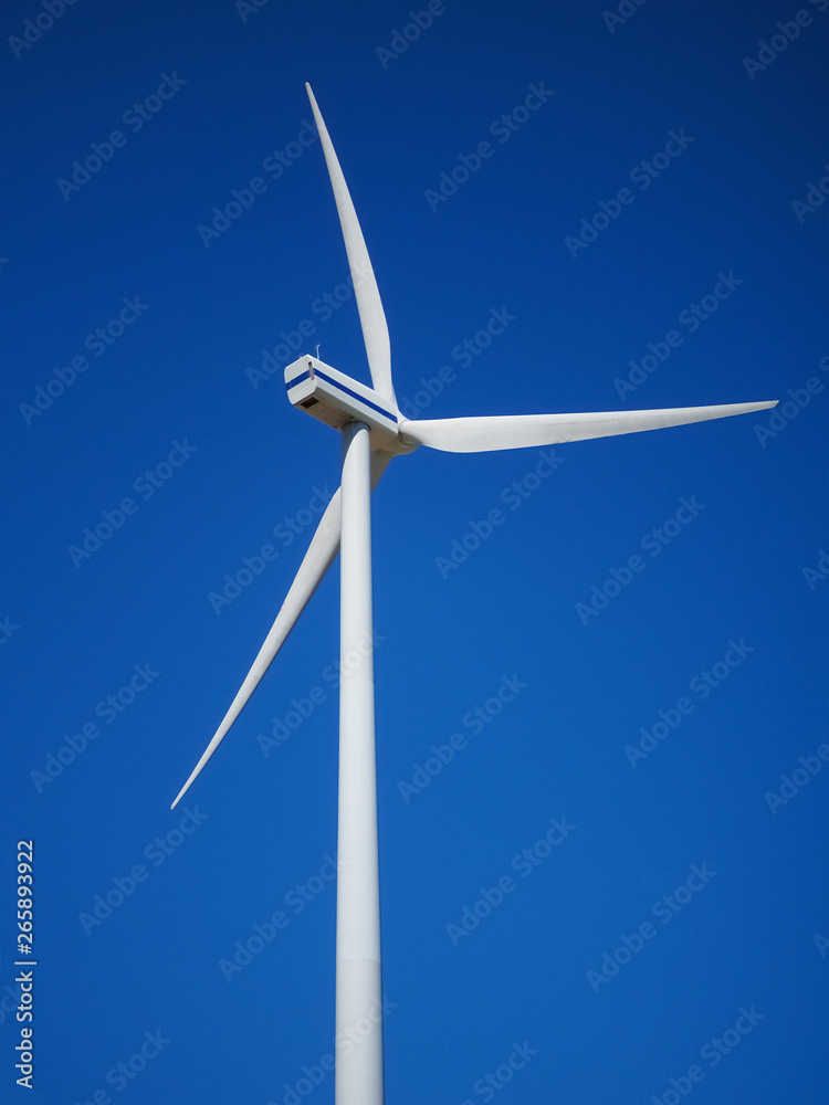 Wind power generator on an empty field. Green energy on a sunny day. Blue sky with clouds. Ecology and energy conservation concept. Wind power generator on an empty field. Green energy on a sunny day. Blue sky with clouds. Ecology and energy conservation concept.