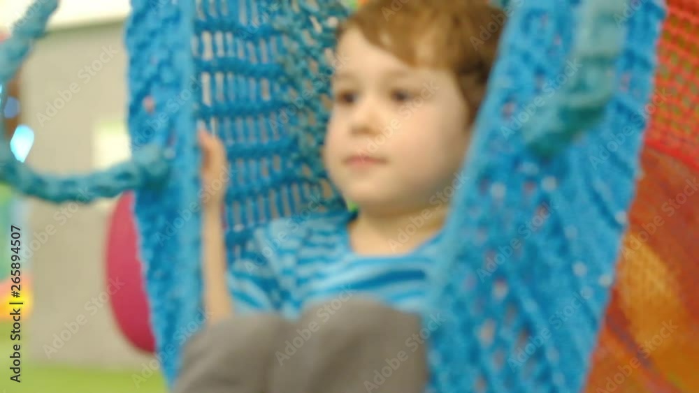 sad boy three years old, swinging on a swing alone in the children's room. lonely child without friends sad boy three years old, swinging on a swing alone in the children's room. lonely child without friends