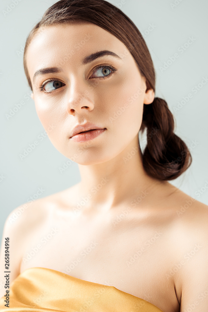 portrait of young woman with shiny lips and golden eye shadow isolated on grey