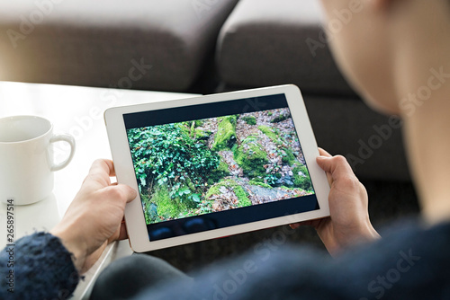 Woman looking at photo on digital tablet, partial view