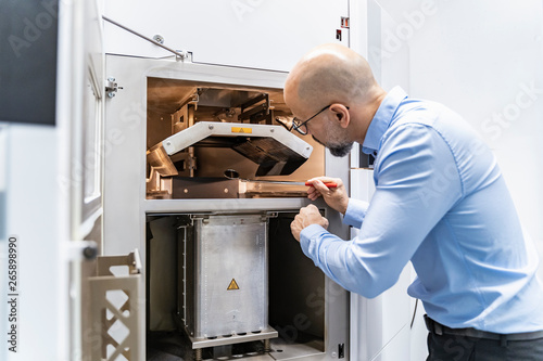 Man holding mirror examining d printer photo