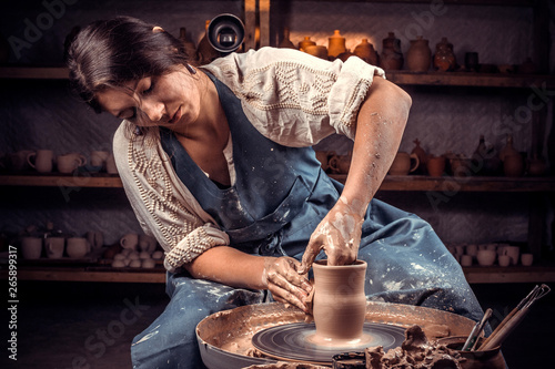 Charming handicraftsman shows how to work with clay and pottery wheel. Making ceramic dishes. photo