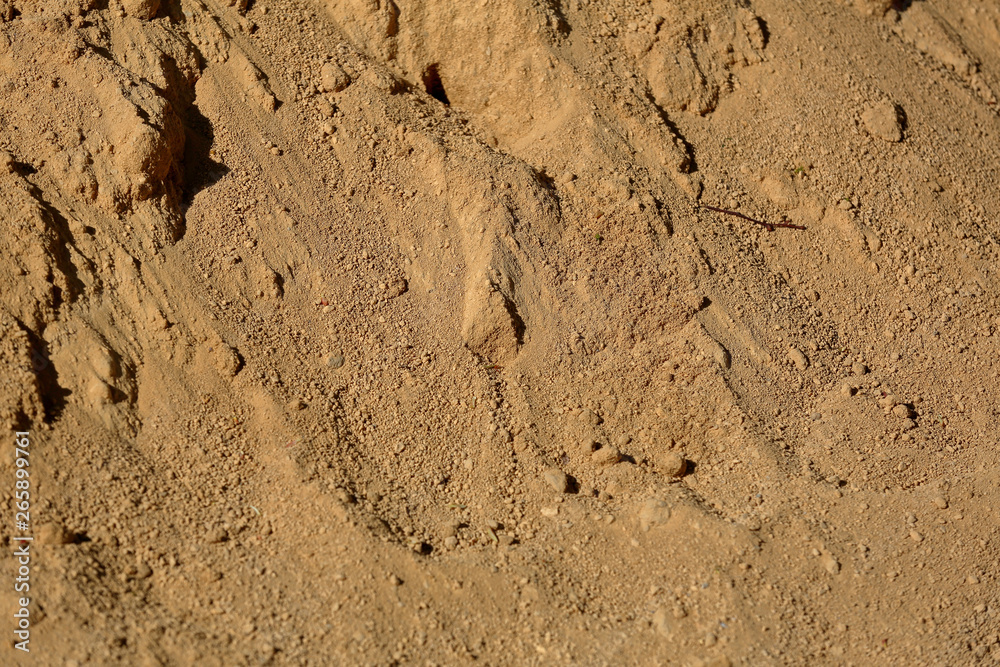 Uneven textured surface of a mixture of dirty sand and small stones