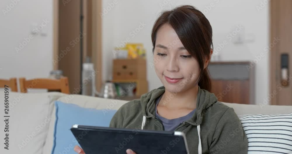 Woman look at the tablet computer and sit on sofa at home Woman look at the tablet computer and sit on sofa at home