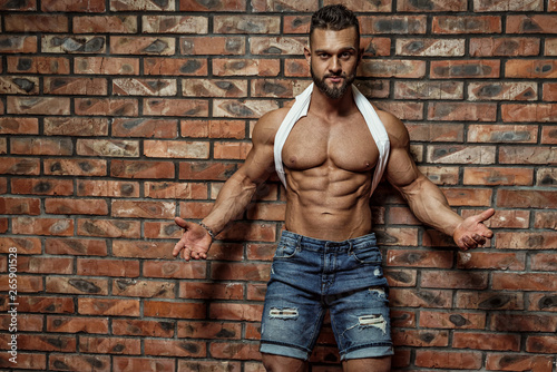 Portrait of strong healthy handsome Athletic Man Fitness Model posing near Brick wall