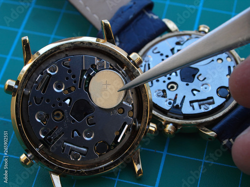 watchmaker replacing watch battery, close up of battery and quartz watch caliber photo