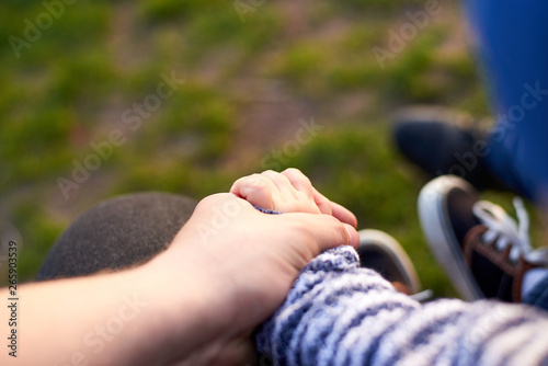 Dad is holding the hand of his son outdoors, parental love concept