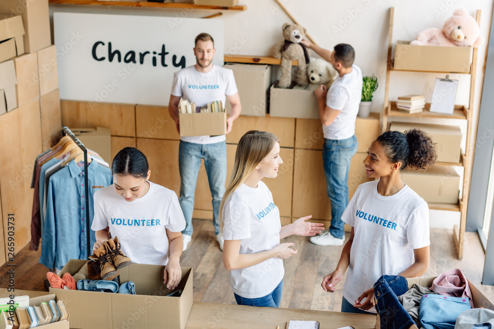 group of young multicultural volunteers in white t-shirts with volunteer inscriptions working in charity center group of young multicultural volunteers in white t-shirts with volunteer inscriptions working in charity center