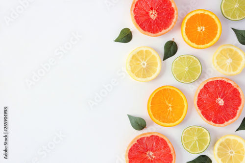 Colorful fruit frame of fresh citrus slices with leaves. Top view  flay lay over a white background with copy space.