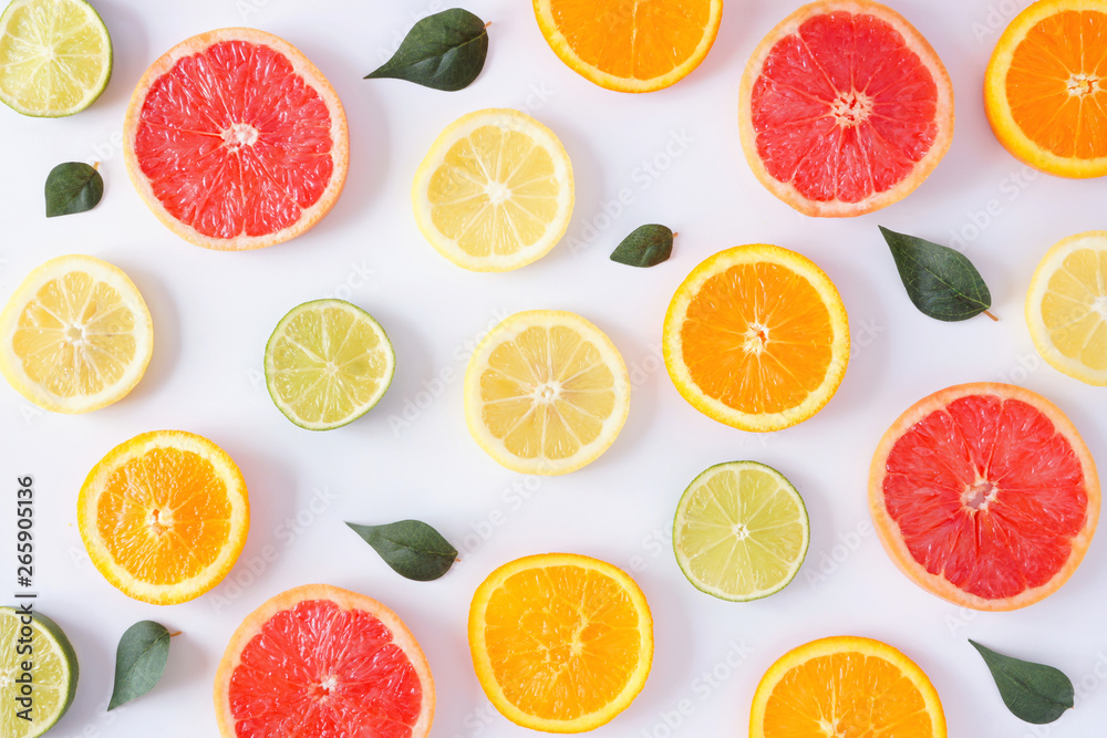 Colorful fruit pattern of fresh citrus slices with leaves. Top view, flay lay over a white background with copy space.