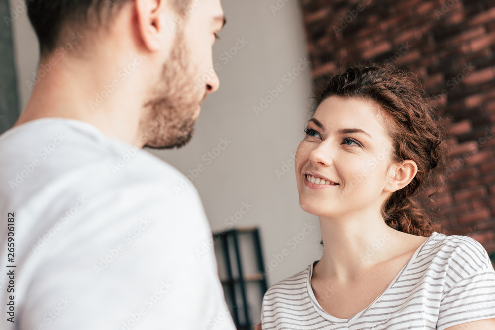 Naklejka premium joyful attractive girl looking at boyfriend with smile