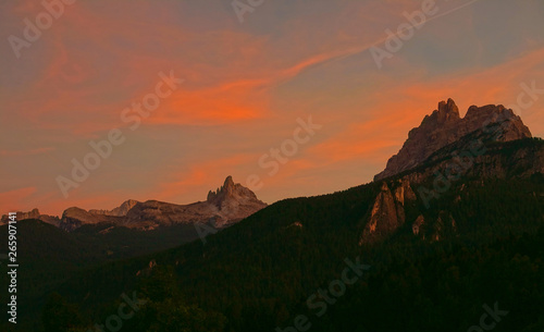 AERIAL  Flying above the dense coniferous forest in the Dolomites at sunset.