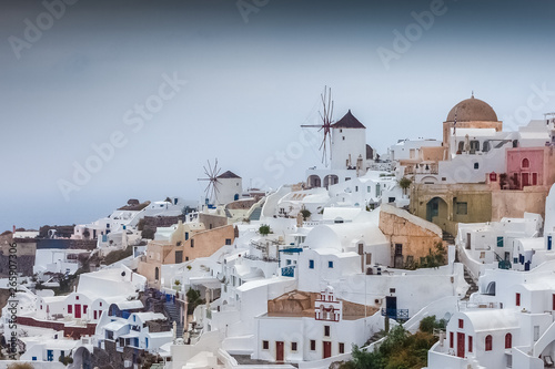 Windmills in the colorful and pictoresque village of Oia on a rare rainy day