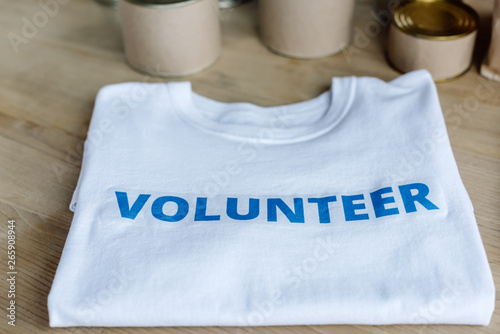 selective focus of white t-shirt with blue volunteer inscription on wooden table