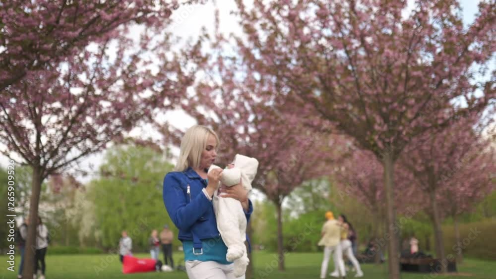 Young mother woman enjoying free time with her baby boy child - Caucasian white child with a parent's hand visible - Dressed in white overall with hearts, mom in blue Young mother woman enjoying free time with her baby boy child - Caucasian white child with a parent's hand visible - Dressed in white overall with hearts, mom in blue