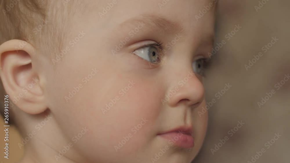 side view close-up portrait of an adorable baby boy who is looking in front of him and then turns his head looks into camera in slow motion 4K video. side view close-up portrait of an adorable baby boy who is looking in front of him and then turns his head looks into camera in slow motion 4K video.
