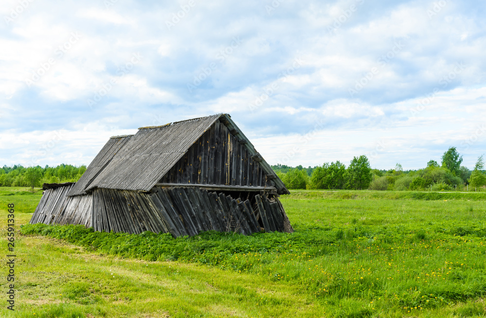 An old rickety barn that's about to fall apart stands in the middle of the field