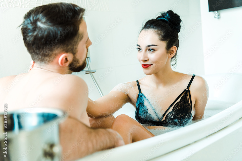 selective focus of happy girl looking at bearded man in bathtub selective focus of happy girl looking at bearded man in bathtub