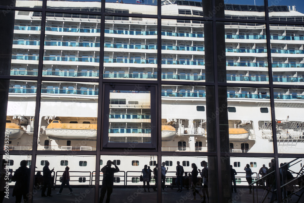 Cruise ship and people silhouettes reflected in port building