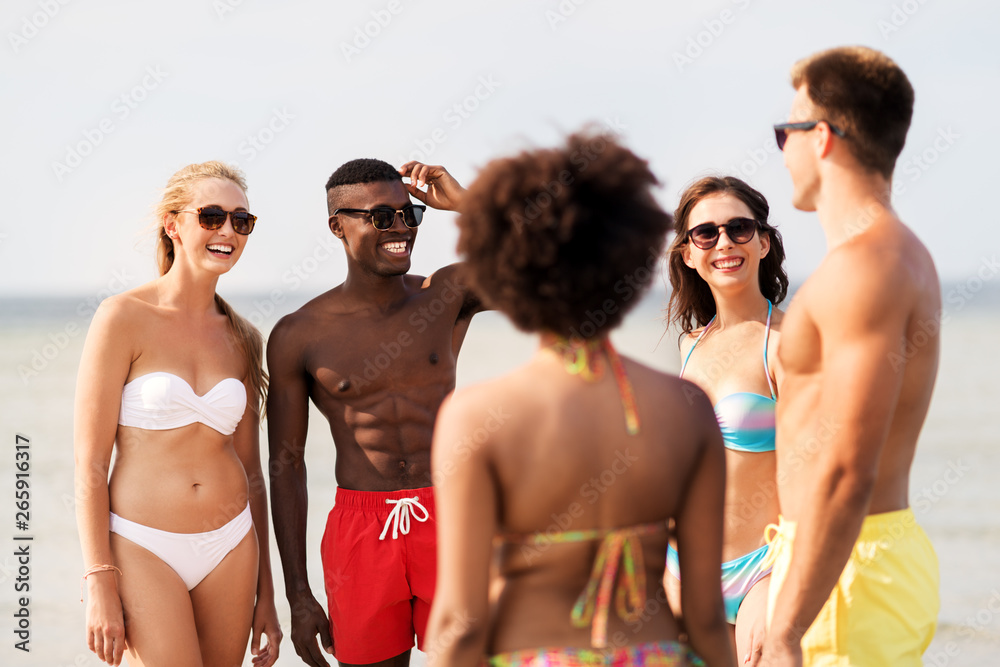 friendship, summer holidays and people concept - happy friends hugging on beach