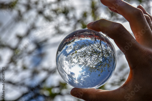 hand holding crystal ball up to the sky 