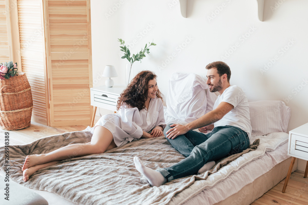 smiling couple lying on bed and looking at each other smiling couple lying on bed and looking at each other