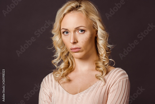 upset blonde woman looking at camera isolated on black
