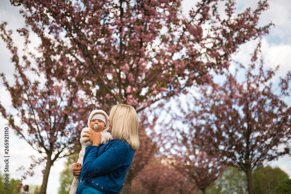 Young mother woman enjoying free time with her baby boy child - Caucasian white child with a parent's hand visible - Dressed in white overall with hearts, mom in blue Young mother woman enjoying free time with her baby boy child - Caucasian white child with a parent's hand visible - Dressed in white overall with hearts, mom in blue