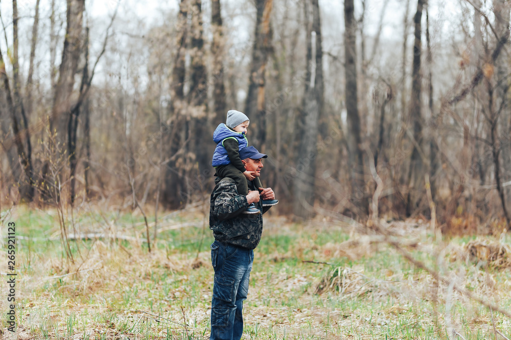 Happy weekend concept. happy grandfather and grandson are walking in forest. Spring. Grandpa rolls on the shoulders of a little boy